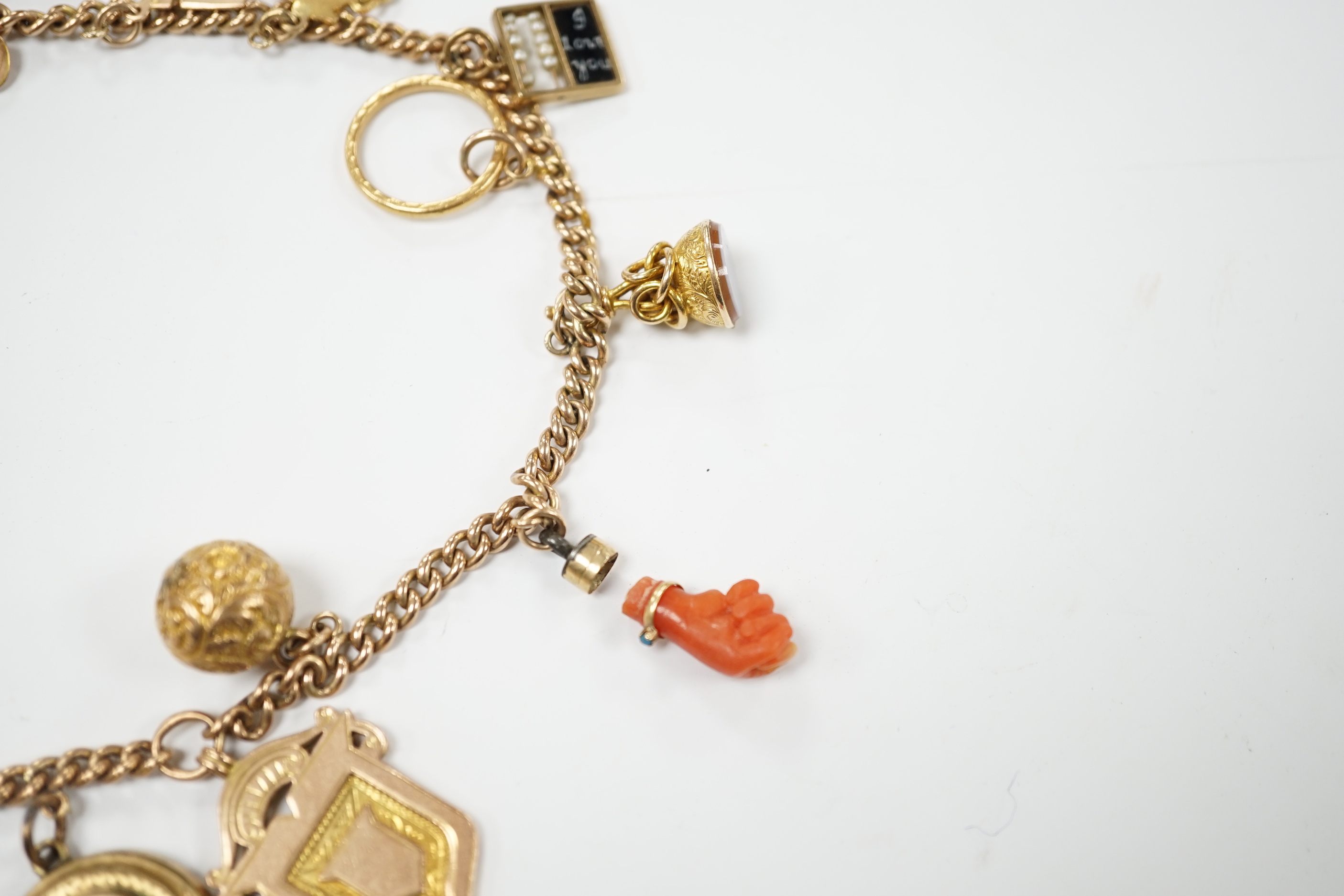A 9ct gold curblink chain hung with fifteen assorted charms including a 1906 sovereign and an 1865 20 francs coin, gross 80.8 grams